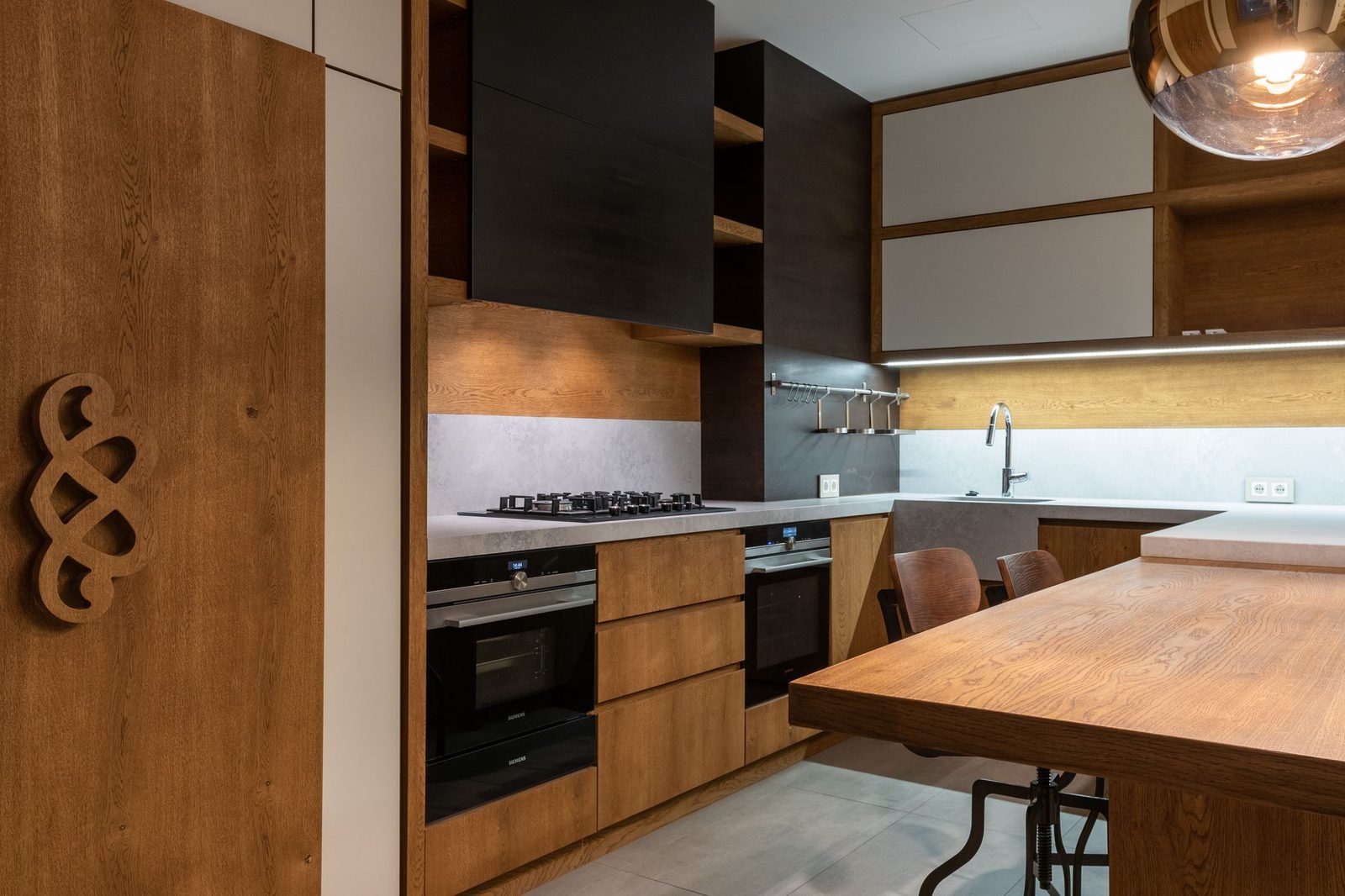 A bespoke handmade dark-wood kitchen with warm under-unit lighting