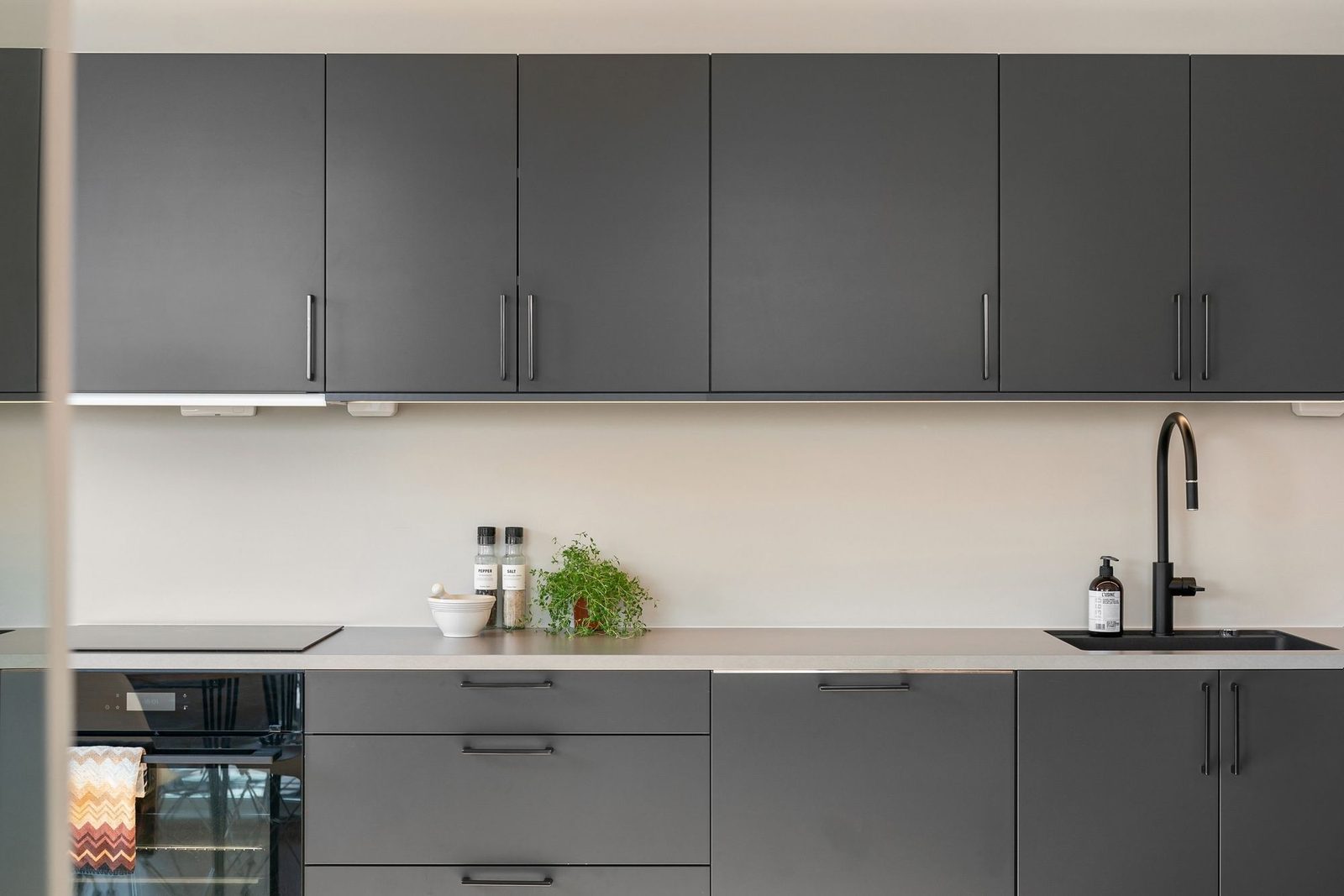 A refurbished modern grey kitchen with slab doors and black tap