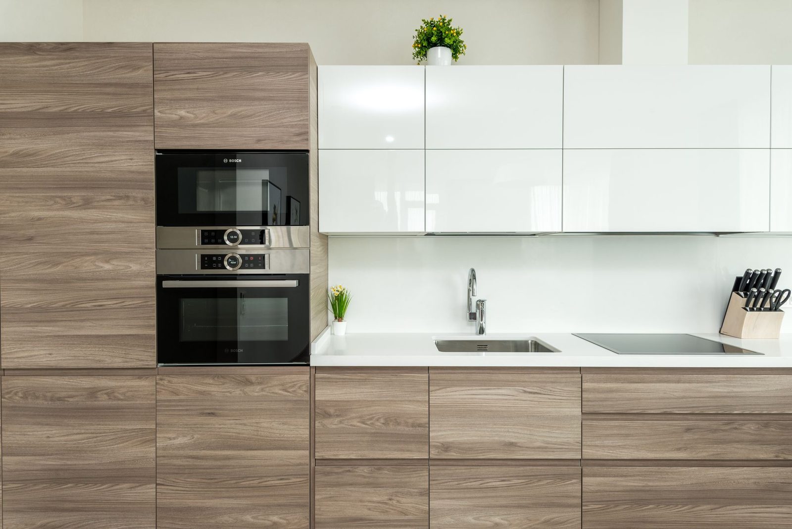 A clean white kitchen worktop run with woodgrain units below